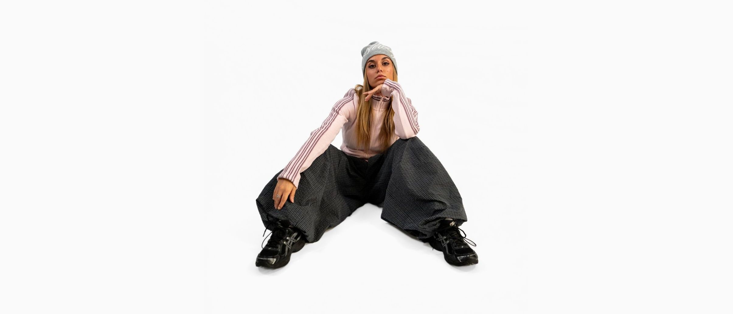 Danseuse assise au sol, bonnet gris, pantalon large